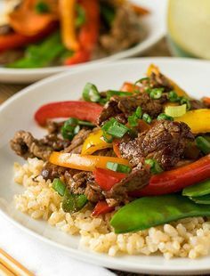 a white plate topped with rice covered in meat and veggies next to chopsticks