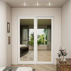 a bedroom with white walls and doors leading to another room that has an outside patio