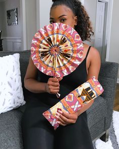 a woman sitting on a couch holding a decorative fan