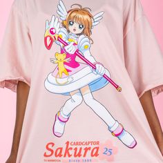 Celebrate 25 years of Cardcaptor Sakura with our Cardcaptor Sakura Ruffle T-Shirt Dress featuring a full front graphic of Sakura Kinomoto alongside Kero-chan, her Sealing Staff and the Cardcaptor Sakura 25th Anniversary logo. Complete with cute ruffles on the sleeve, this pretty pink t-shirt dress can also be worn as an oversized t-shirt, just size down! Oversized Fit Printed Details 100% Cotton Ruffled Detail Officially licensed Cardcaptor Sakura product ⓒC, ST/K, EP, N Model Sizes: Model 1: SMALL Model 2: LARGE Pink Crew Neck T-shirt For Cosplay, Pink Anime Style Tops With Character Print, Pink Anime Character Print T-shirt, Anime Style Pink T-shirt With Character Print, Pink Cotton Anime T-shirt, Pink Anime Cotton T-shirt, 25th Anniversary Logo, Kero Chan, Pink T Shirt Dress