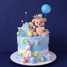 a teddy bear sitting on top of a blue cake with balloons in the shape of stars