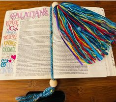 an open book with tassels on top of it and the word galatians written in multicolored letters