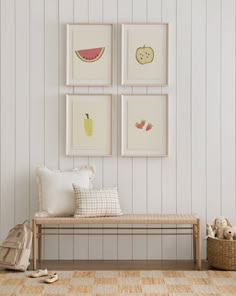 four framed pictures hang on the wall above a bench with pillows and stuffed animals nearby