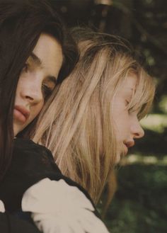 two young women standing next to each other with long hair and white gloves on their shoulders