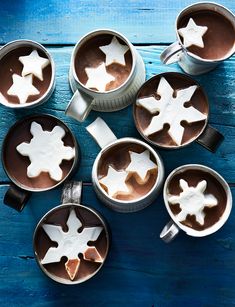 hot chocolate with marshmallows in mugs on blue wooden background, top view