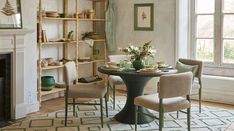 a dining room table with four chairs around it and a fire place in the background