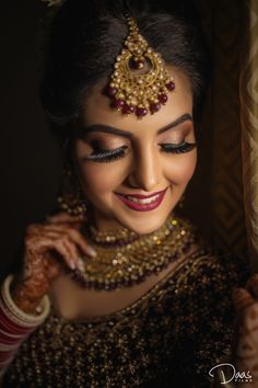 a woman with makeup and jewelry on her face posing for a photo in front of a window