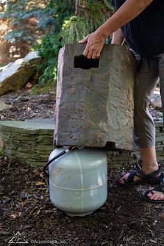 a man is holding a propane tank in the woods