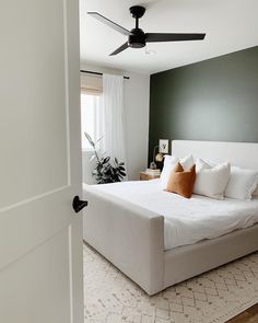 a bedroom with a bed, ceiling fan and rug on the floor in front of it