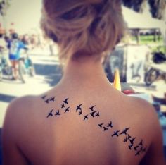 the back of a woman's neck with birds on her upper and lower part