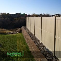 a long white fence next to a grassy field