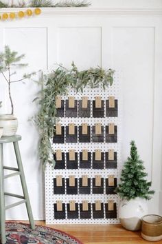 a christmas tree is sitting next to a calendar on a wall with clothes pins pinned to it