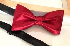 "Gorgeous Burgandy Satin Bow Tie These bow tie has been design in satin. The Unisex bow ties are an excellent evening addition to any wardrobe.  3 colors available use drop-down menu when ordering.  Our bow ties are made in fine satin with interfacing to give it, stability and shape. And make a perfect gift.  Colors available: Red Silver  Black Approximate Measurements: Bow: 5\" x 2.5\" Adjustable Strap: 14\" x 19\" Bow Tie care : Dry Clean only. We Love Custom Packages Orders All items are sent Red Bow Tie For Party, Red Bow Standard Bow Tie For Party, Red Adjustable Tie For Wedding, Adjustable Red Ties For Wedding, Red Adjustable Ties For Weddings, Adjustable Red Suit And Tie Accessories For Wedding, Red Adjustable Wedding Ties, Red Party Tie With Bow Tie Back, Red Bow Suit And Tie Accessories For Party