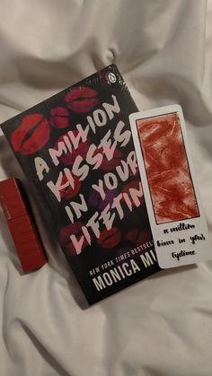 there is a book and lipstick on the bed with it's cover pulled down