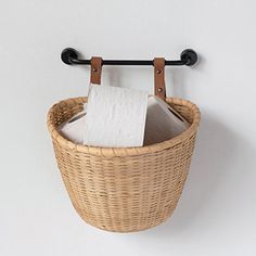 a wicker basket hanging on the wall with a roll of toilet paper in it