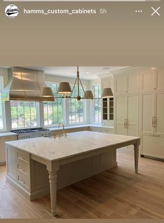 a large kitchen with an island in the middle and two pendant lights hanging from the ceiling