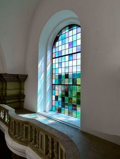 a stained glass window sitting in the corner of a white wall next to a stair case