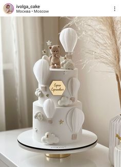 there is a white cake decorated with hot air balloons and teddy bears on the top