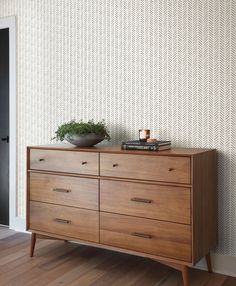 a wooden dresser sitting in front of a wall with a plant on top of it