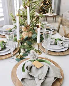 a christmas table setting with candles, plates and napkins