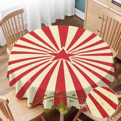 a red and white striped umbrella sitting on top of a wooden table next to chairs