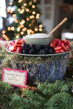 a bowl filled with berries sitting on top of a table next to a christmas tree