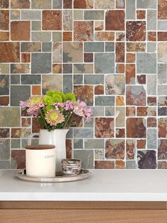 a vase filled with flowers sitting on top of a counter next to a tiled wall