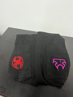 two black pants with red and pink logos on them sitting on top of a table