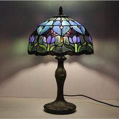 a stained glass lamp on a table with a white wall in the backround