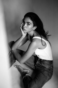 a black and white photo of a woman sitting on the floor with her hand under her chin