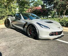 a white sports car parked in a parking lot next to some trees and shrubbery