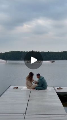 a man and woman sitting on top of a pier