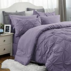 a bed with purple comforter and pillows