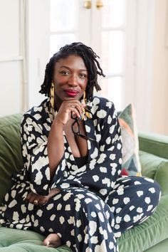 a woman sitting on top of a green couch wearing black and white polka dot pajamas