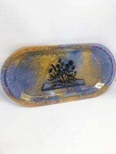 a blue and gold tray with flowers painted on the bottom is sitting on a white surface