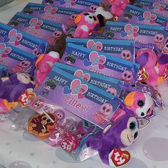 many pink and purple stuffed animals are on a table with birthday cards in front of them