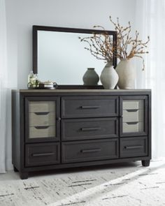 a dresser with two vases and a large mirror on it's sideboard