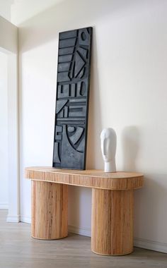 a wooden table sitting next to a white vase on top of a hard wood floor