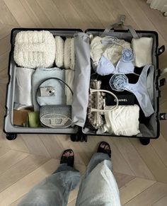 an open suitcase filled with clothing and other items on top of a hard wood floor