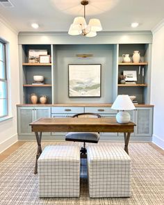 a living room with two chairs and a table in the middle, built in shelving units