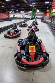 several people are riding bumper cars in an indoor area with red and black seats on them