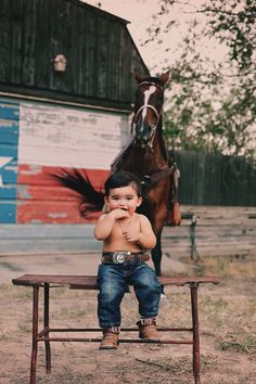 a young boy sitting on a bench in front of a horse