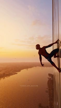 a man climbing up the side of a tall building in front of a body of water