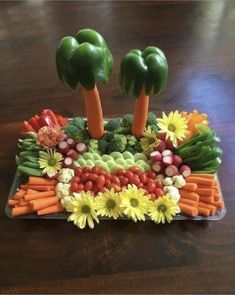 a platter filled with vegetables and fruit on top of a wooden table in the shape of palm trees