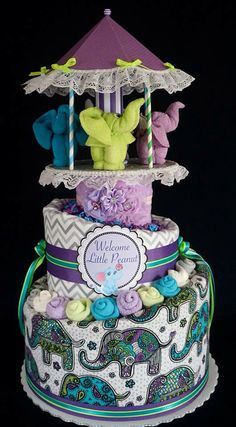 a three tiered cake with an elephant on it's side and rainbow decorations