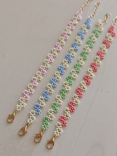 four different colored beads with gold hooks on a white surface, each beaded in various colors and sizes