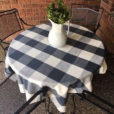 a table with a checkered cloth on it and a white vase filled with flowers