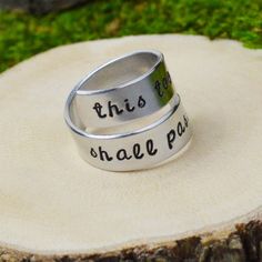 two silver rings with words on them sitting on top of a piece of tree stump