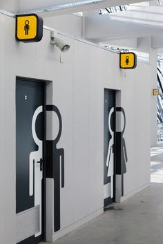 three restroom stalls with black and white designs on them, one has a yellow sign above the door