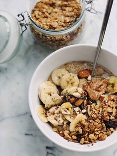 a bowl filled with granola and nuts next to a glass jar full of oatmeal